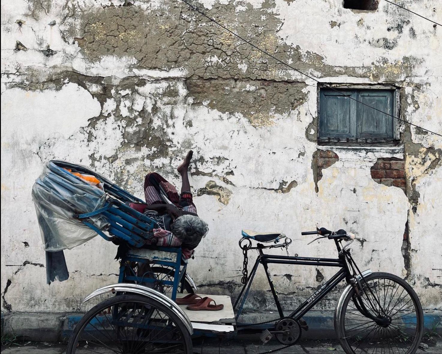 A Rickshaw driver taking his afternoon nap on a sunny day.