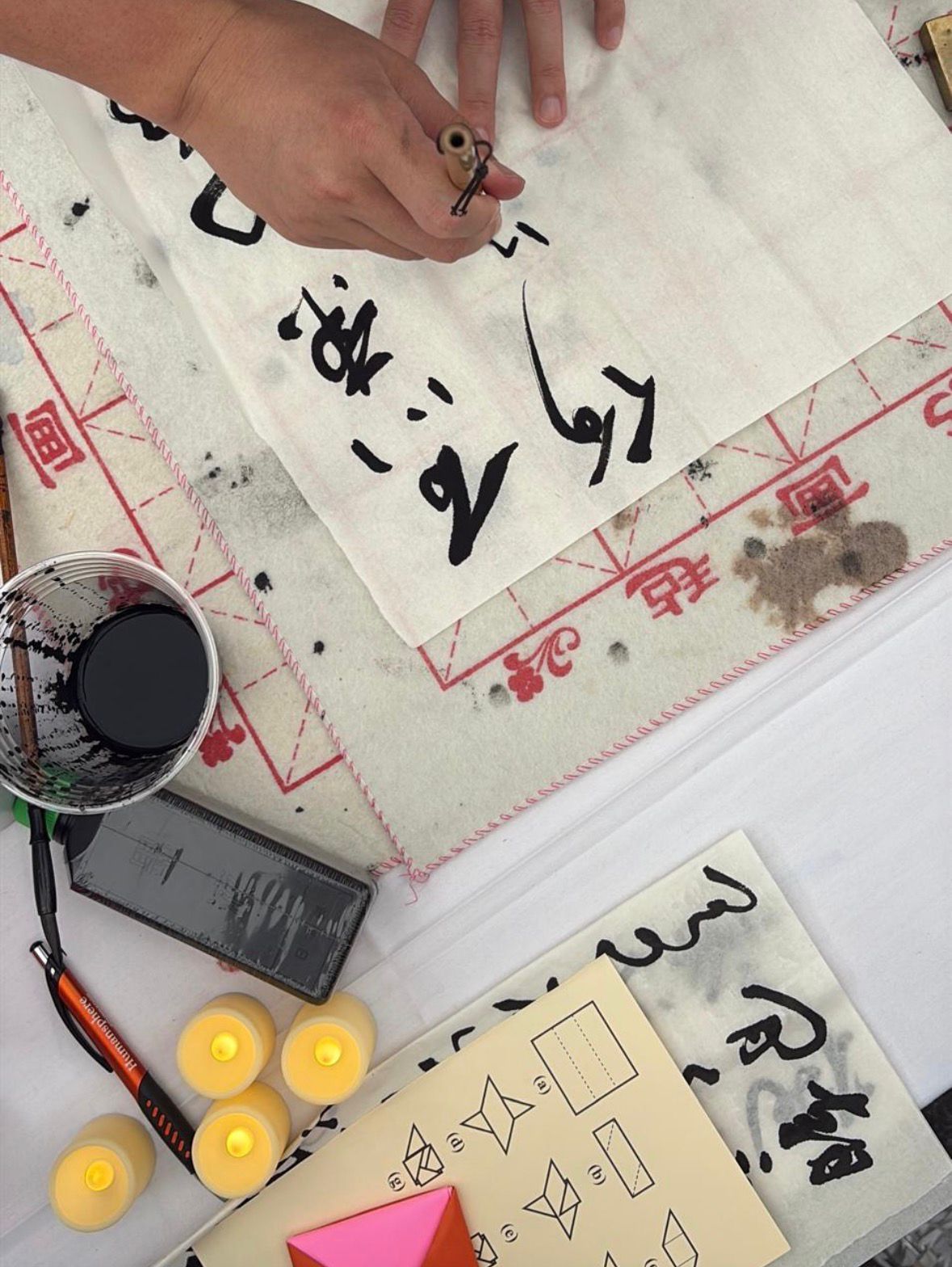 An artist at Harvard square practising the art of calligraphy and origami.
